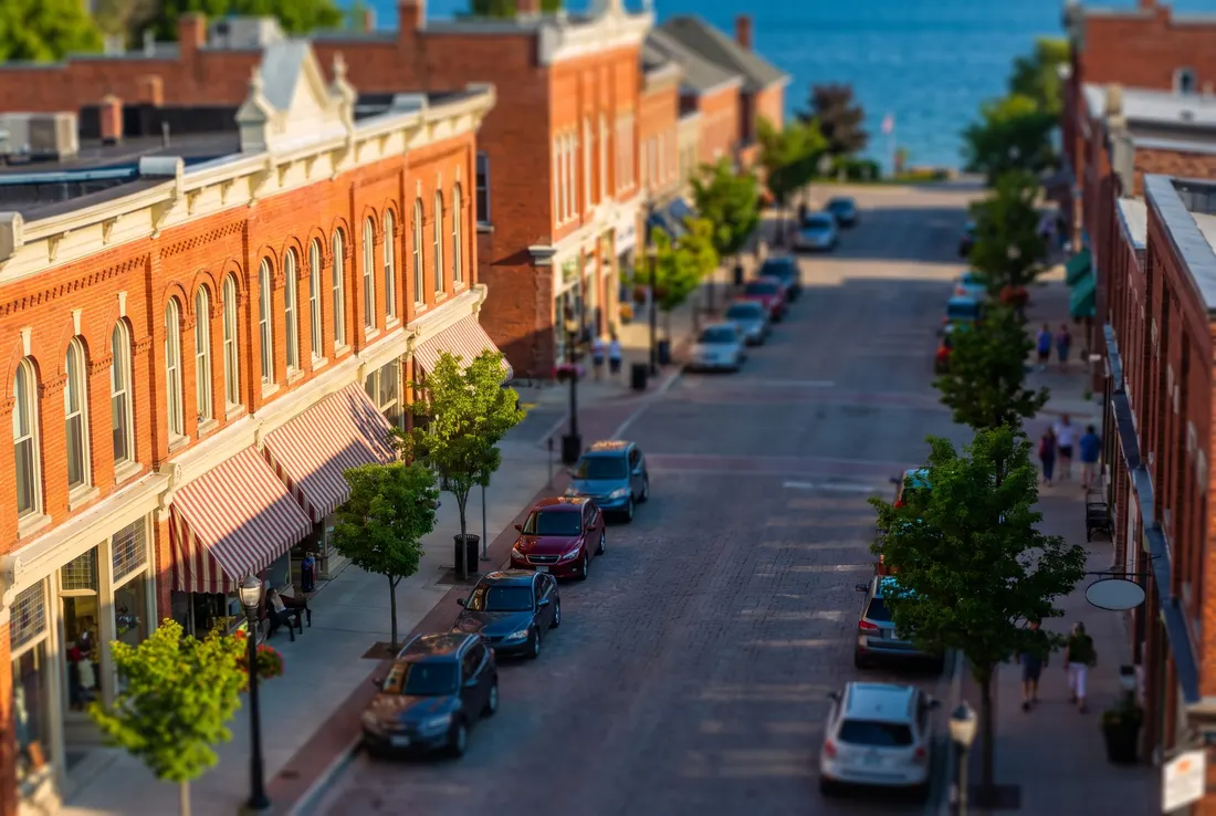 Red-brick main street shops with awnings near a lake